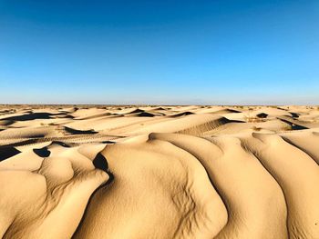 Scenic view of desert against clear blue sky