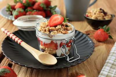 Strawberry parfait with granola and yoghurt, close up on wooden table. summer snack concept