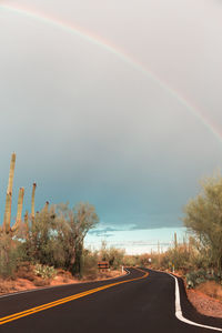 Rainbow over road against sky