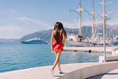 Woman standing by sea against sky