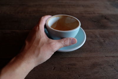 Midsection of person holding tea cup on table