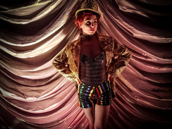 Portrait of young woman standing against illuminated wall