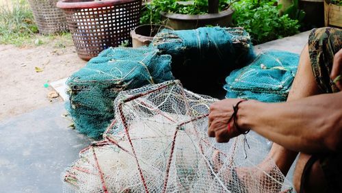 Low section of man holding fishing net sitting outdoors