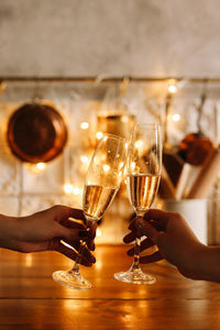 The clinking of glasses with champagne wine against the background of christmas garlands