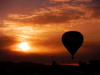 Silhouette hot air balloon against orange sky