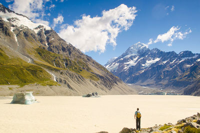 Rear view of man standing on mountain against sky