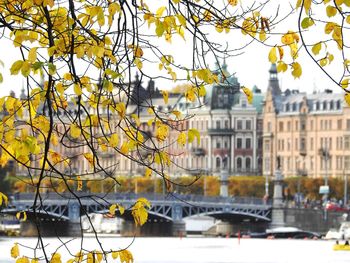 Bridge over river by buildings against sky