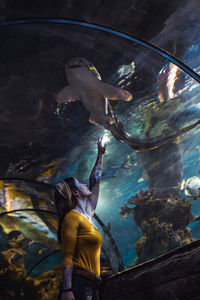 Full length of young woman looking at shark  swimming in aquarium