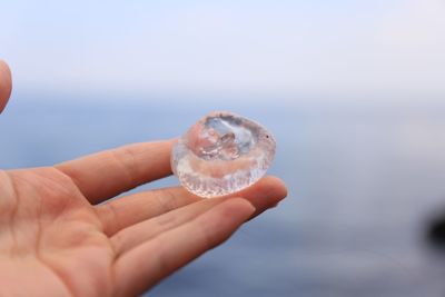 Cropped hand holding ice outdoors