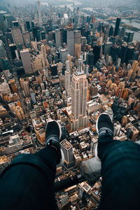 Low section of man sitting against buildings in city