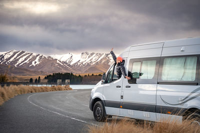 Asian women pose with her camper van for road trip vacation at new zealand south island.