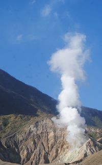 Smoke emitting from volcanic mountain against sky