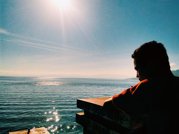 Man looking at sea against sky during sunset