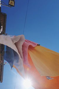 Low angle view of sun against clear blue sky