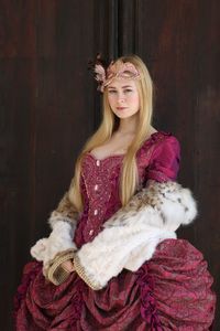 Portrait of beautiful woman wearing pink costume standing against wall