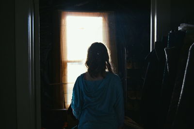 Rear view of woman standing against window in building