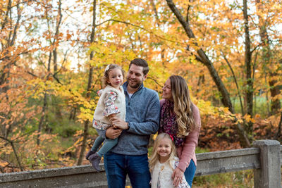 Happy family standing against trees