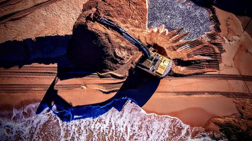 Aerial view of earthmover by rock at beach