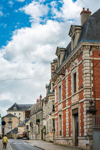 Street by buildings in town against sky