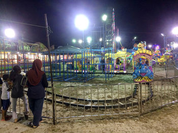 Men standing in illuminated park against sky at night