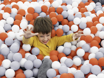 High angle view of boy sitting in ball pool