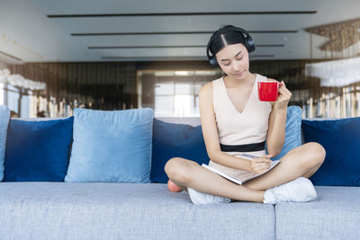 Young woman sitting on sofa at home