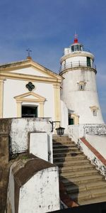 Low angle view of lighthouse amidst buildings against sky