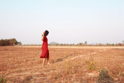 Woman standing on field against clear sky