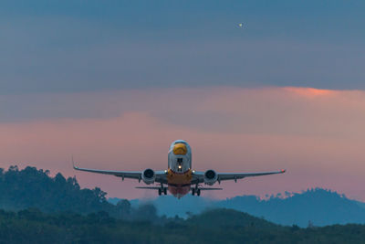 Airplane flying against sky during sunset