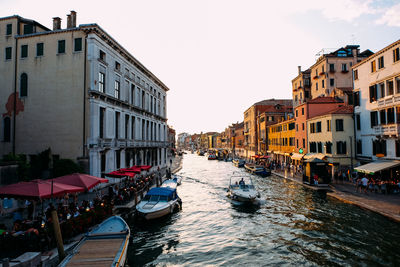 Boats in canal amidst buildings in city