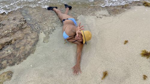 High angle view of shirtless man lying on sand at beach