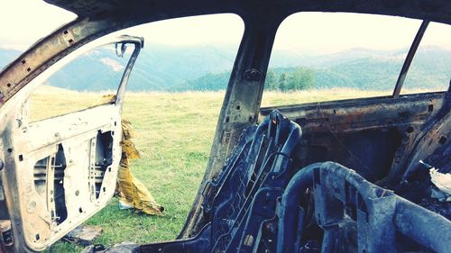 Close-up of abandoned car on landscape against sky