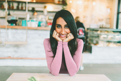 Portrait of smiling young woman sitting at table in cafe