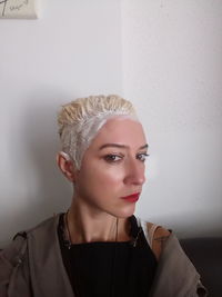 Close-up portrait of woman with dyed hair against wall at home