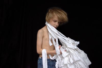 Boy standing against black background