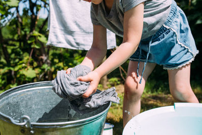 Little preschool girl helps with laundry. child washes clothes in garden