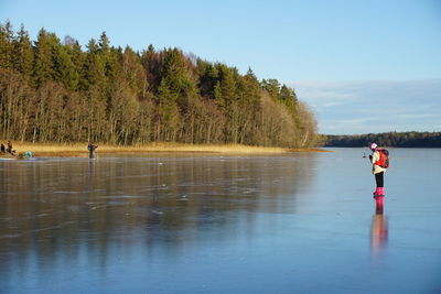 Person ice-skating on frozen lake against sky