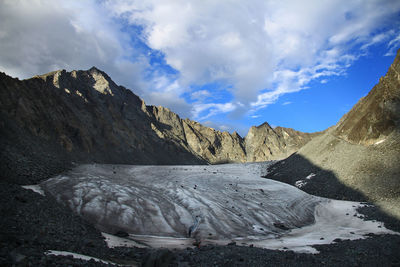 Glacier in an alpine rocky gorge against the background of the sky with clouds