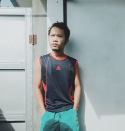 Portrait of young man standing against wall