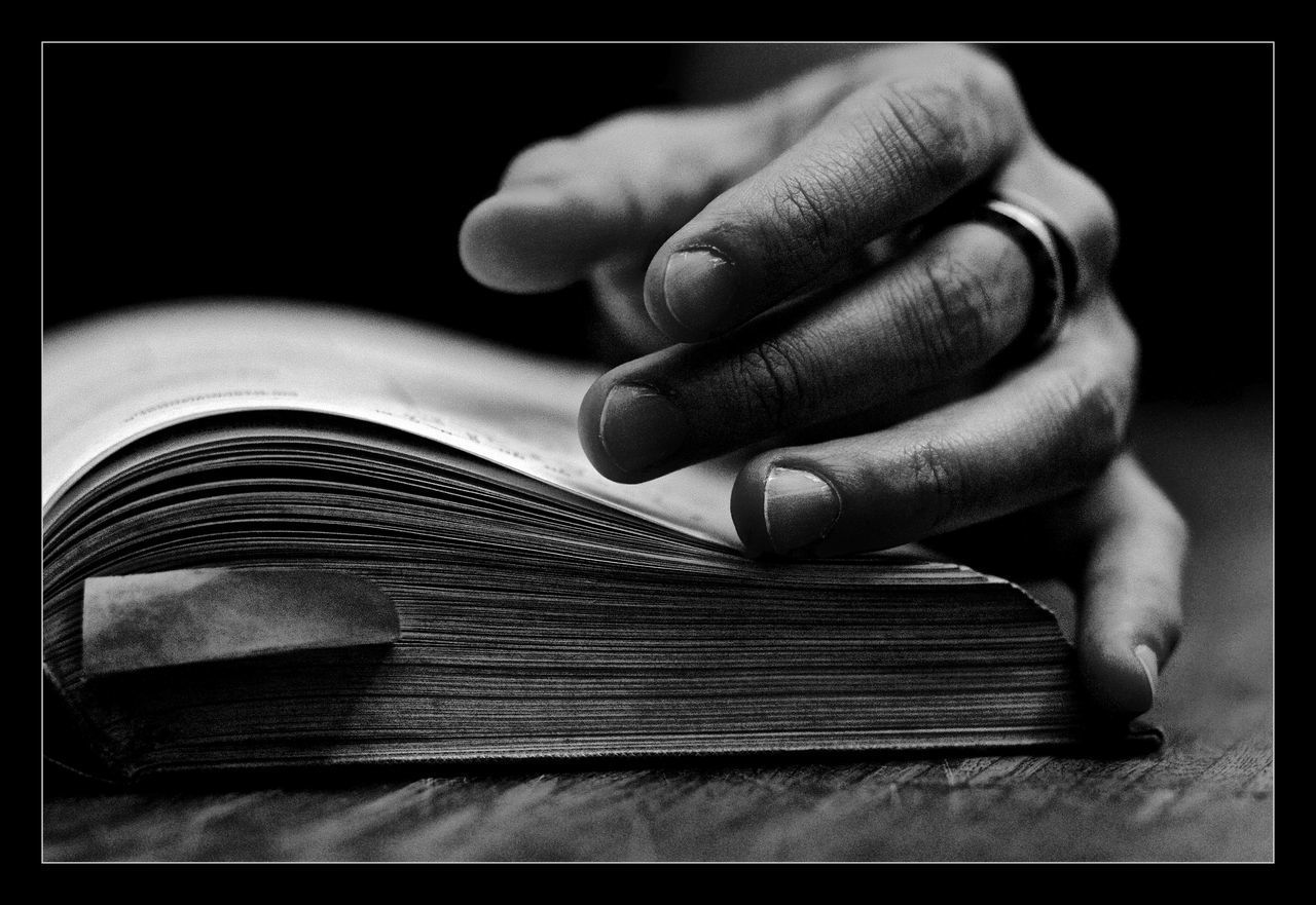 Cropped image of hand on open book at table