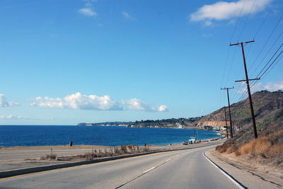 Road by sea against blue sky