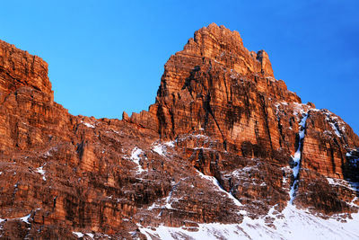 Low angle view of rocky mountain against blue sky