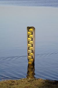 High angle view of information sign on wooden post at lake