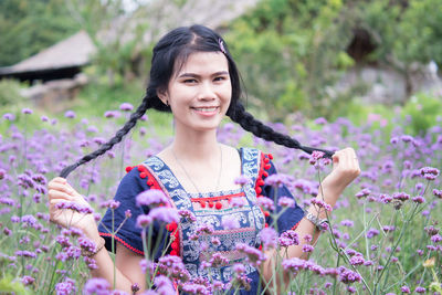 Portrait of smiling woman with pink flowers against plants