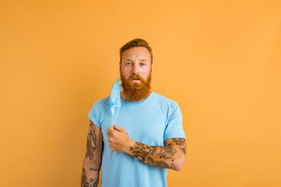 Portrait of man standing against orange background