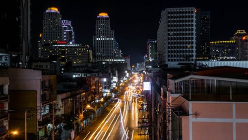 Light trails on road amidst buildings in city at night