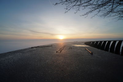 Surface level of road against sky during sunset