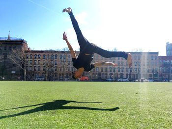 Man jumping in front of buildings against sky