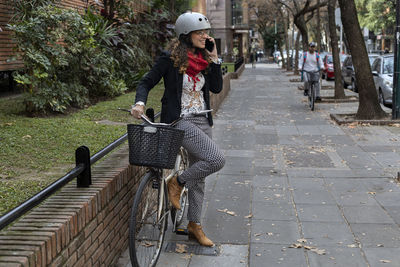 Rear view of woman riding bicycle on footpath