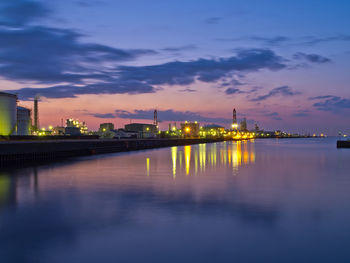 Illuminated city at waterfront during sunset